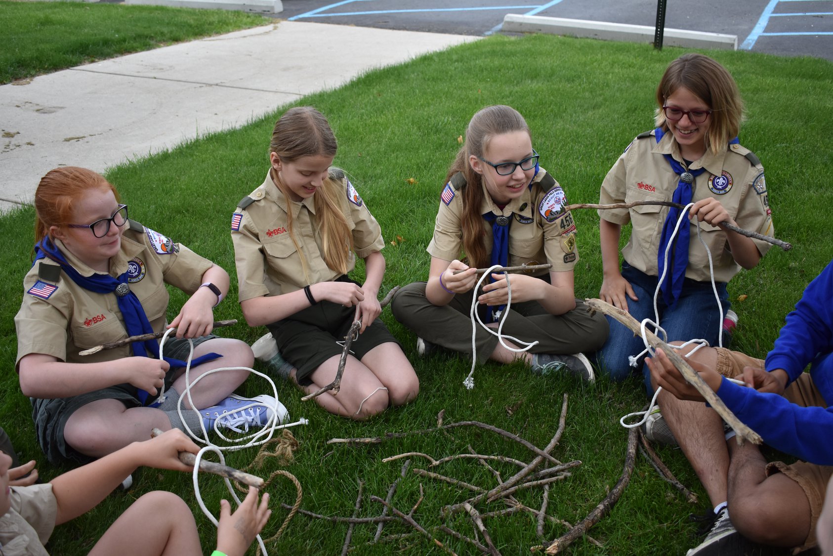 Scouts sitting in a circle practicing knot tying