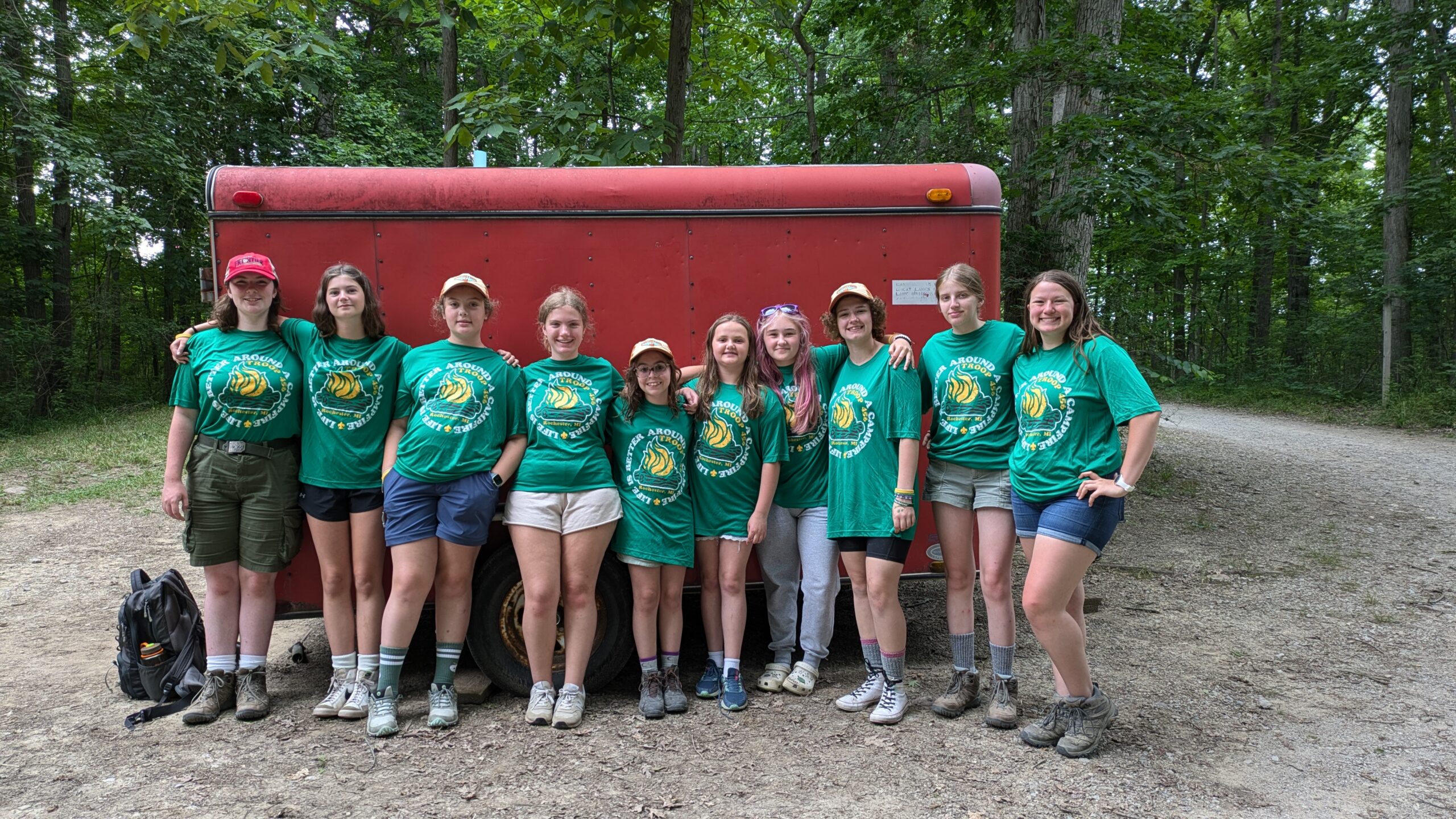 Troop 456 in green camp shirts standing in front of a red trailer