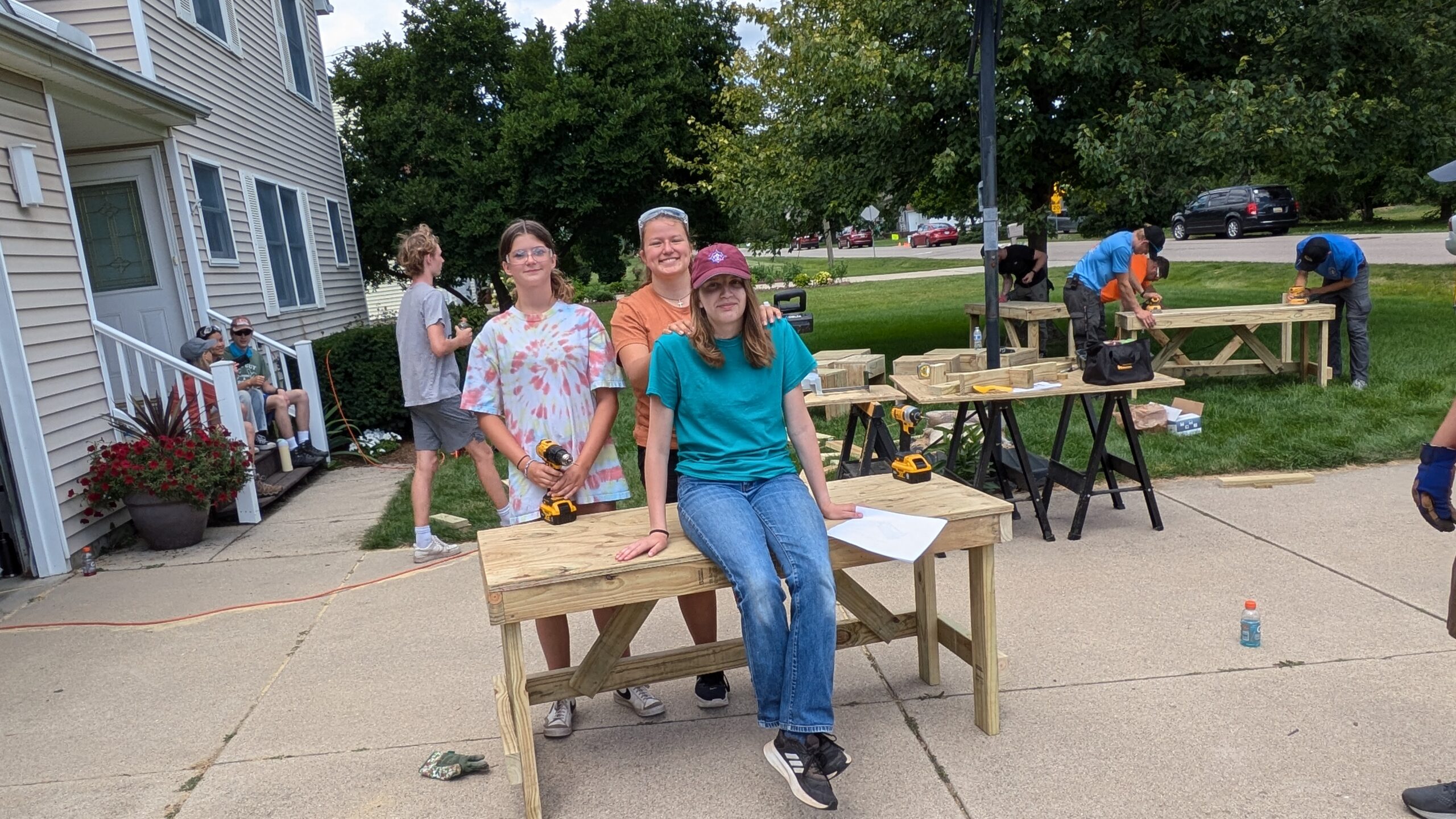 Scout sitting on a table with 2 scouts behind at an Eagle project build day